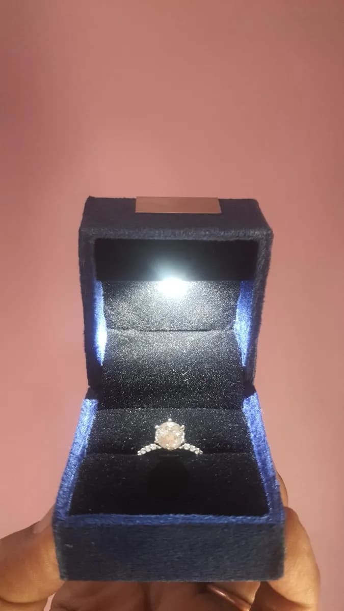 A diamond ring in a lit navy velvet box